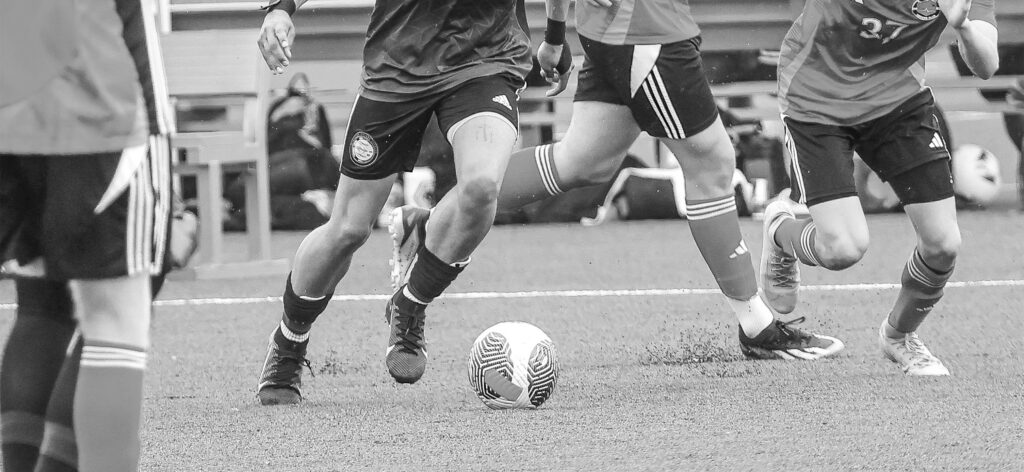 Soccer players dribbling ball up the field